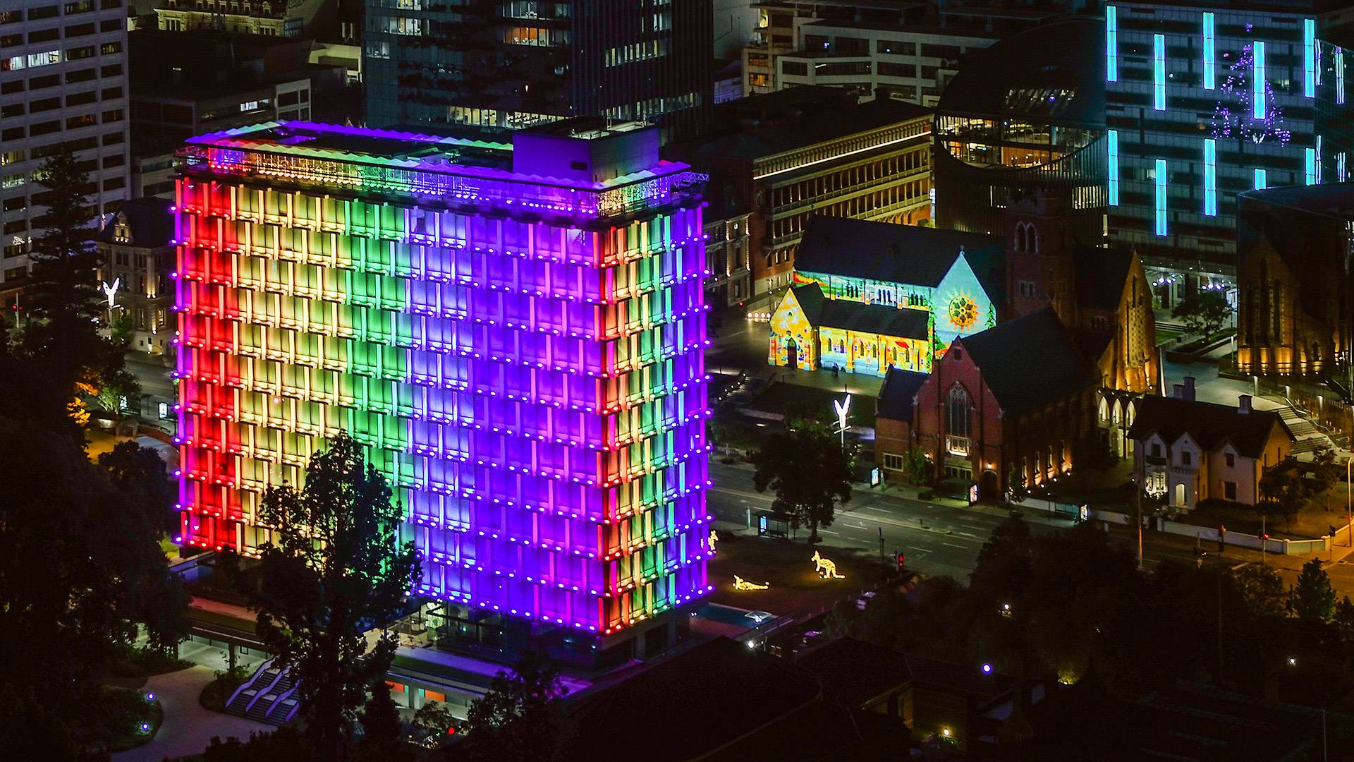 Latitude LED luminaire in application, installed on the facade on Council House in Perth. Colour changing feature is illustrated, the building is illuminated in rainbow colours. 