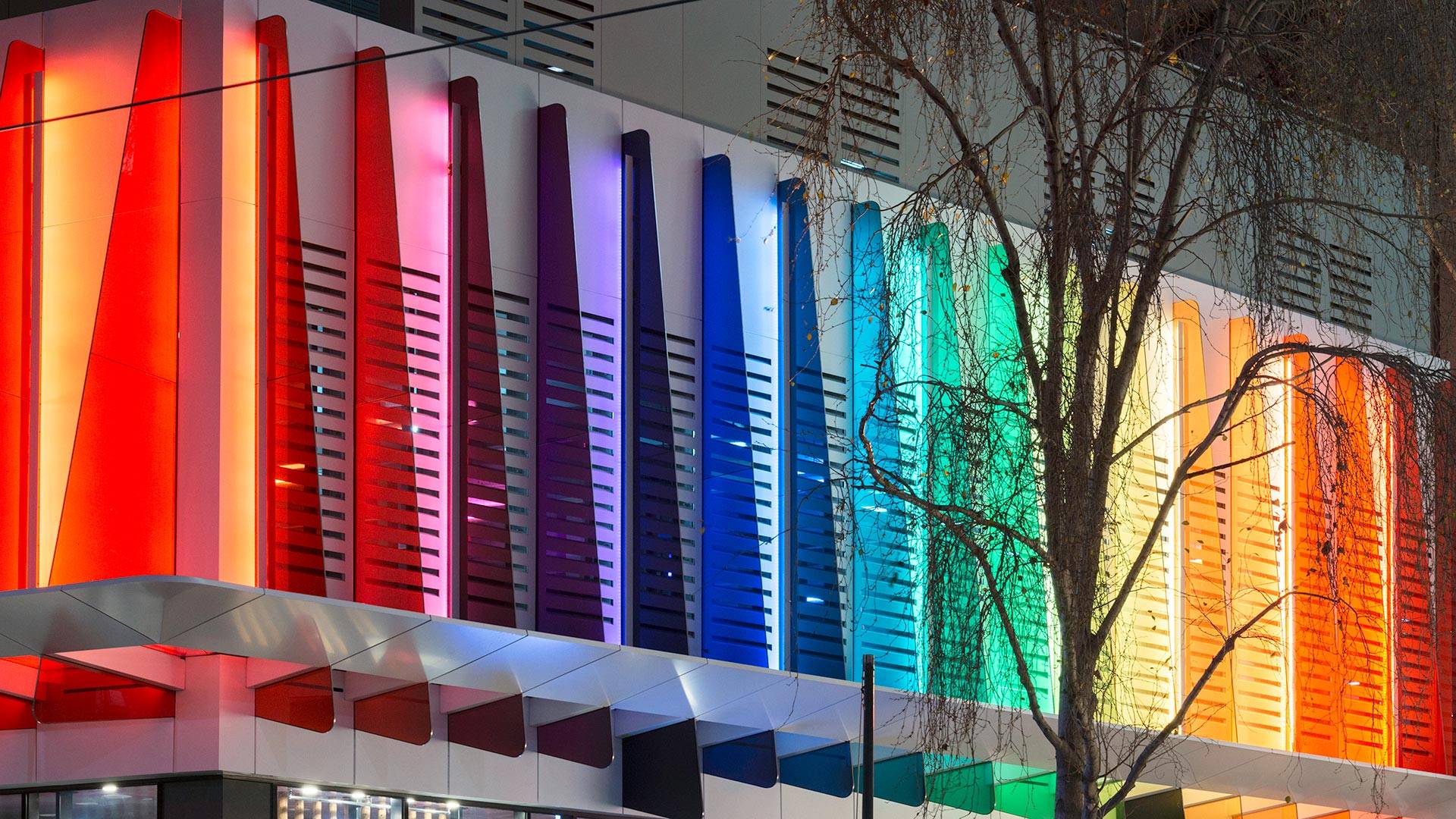 Maxis high-power linear flood light  in application, installed on the Strad Facade in Melbourne CBD. Every second coloured panel is illuminated by a Maxis high-power luminaire.