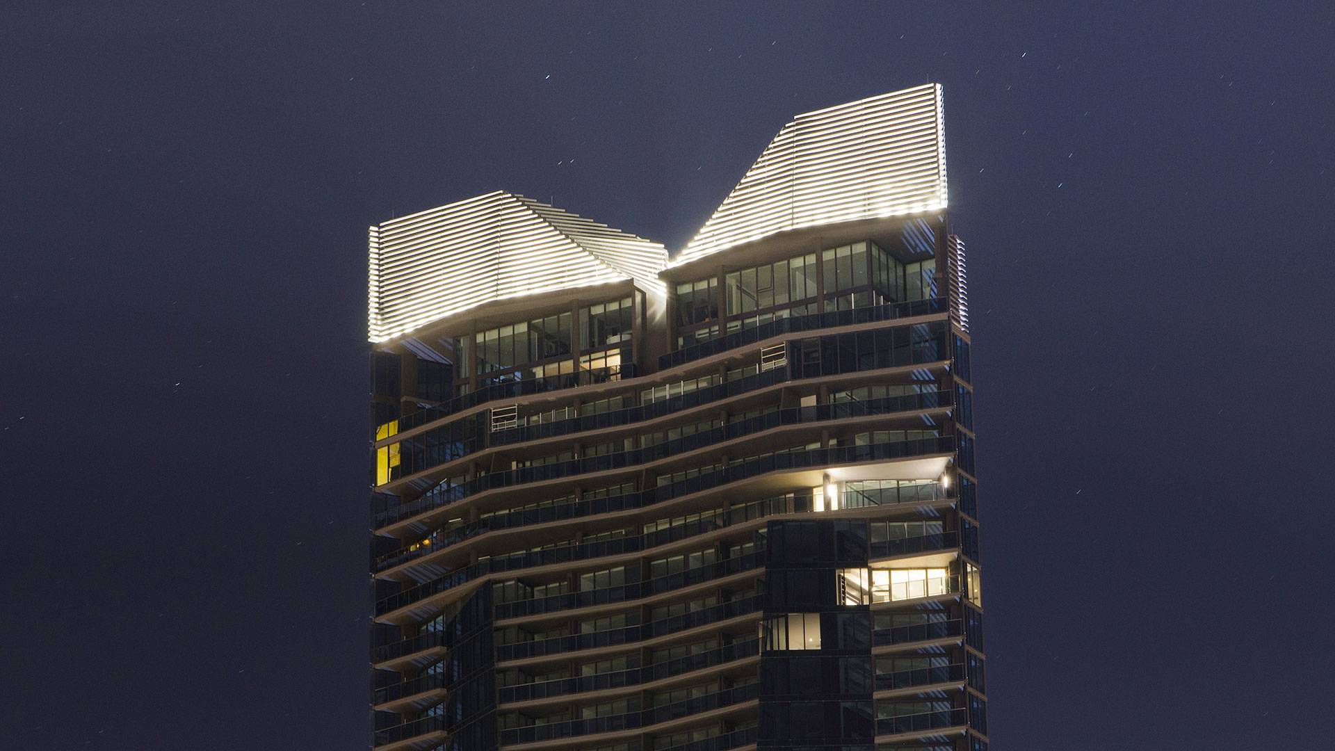 Maxis high-power linear flood light  in application, installed on Yarra Point (Tower 6). Maxis high-powered projector luminaires, complete with flare optics, are used to illuminate the architectural crown of the building.